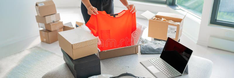 Onlinebutiksförsäljning av kläder på en webbplats som arbetar med datorföretag från hemmet. kvinna som packar nya kläder