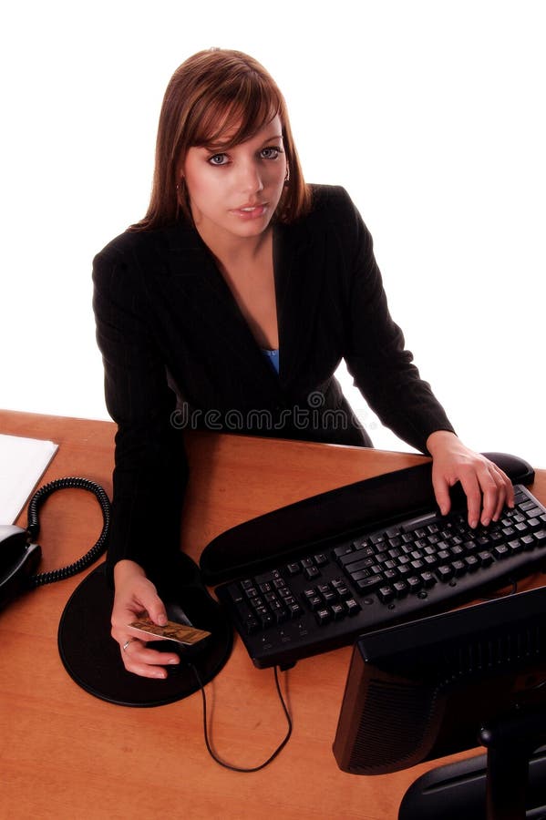 redheaded business woman in black business suit at her desk using a credit card to make an online purchase / ecommerce isolated over white. redheaded business woman in black business suit at her desk using a credit card to make an online purchase / ecommerce isolated over white
