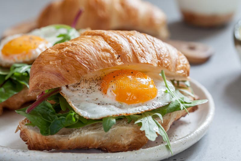 Ontbijt met Croissantsandwiches met Fried Egg, Saladebladeren en avocado royalty-vrije stock fotografie Ontbijt met Croissantsandwiches met Fried Egg, Saladebladeren en avocado royalty-vrije stock fotografie