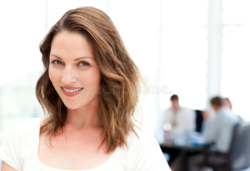 Relaxed businesswoman standing in front of her team while working at a table. Relaxed businesswoman standing in front of her team while working at a table