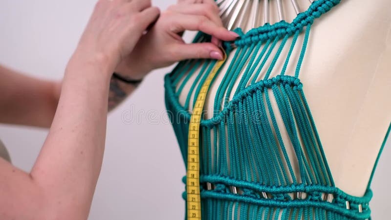 Ontwerper creëert een unieke groene macrame jurk op de dummy in het naaien van een zwarte vrouw met een naaiatelier tijdens de wor