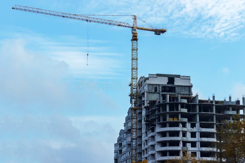 Onvolledige bouwconstructie en de bouwkranen tegen duidelijke blauwe hemelachtergrond stock foto Onvolledige bouwconstructie en de bouwkranen tegen duidelijke blauwe hemelachtergrond stock foto