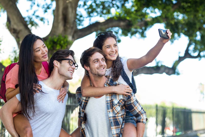 Op de rug aan hun meisjes geven en heupmensen die selfie nemen stock afbeelding Op de rug aan hun meisjes geven en heupmensen die selfie nemen stock afbeelding