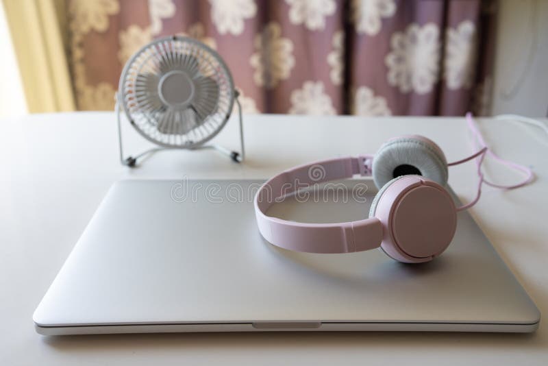 Op een witte lijst is er een ventilator van de metaal witte Desktop, een bloem in een bloempot, gesloten laptop, zijn de getelegr royalty-vrije stock afbeelding Op een witte lijst is er een ventilator van de metaal witte Desktop, een bloem in een bloempot, gesloten laptop, zijn de getelegr royalty-vrije stock afbeelding