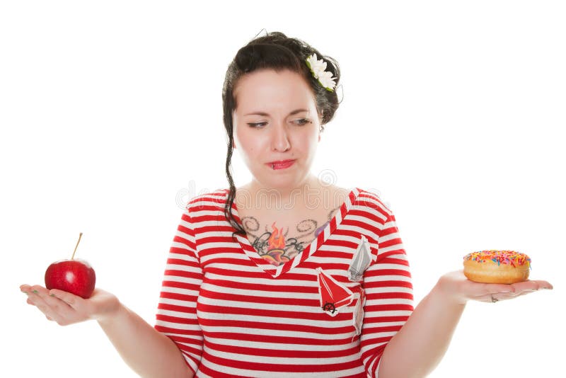 A young, woman, dressed in Rockabilly style, trying to decide whether to eat the tempting, sweet donut, or the healthy, fresh apple. A young, woman, dressed in Rockabilly style, trying to decide whether to eat the tempting, sweet donut, or the healthy, fresh apple.