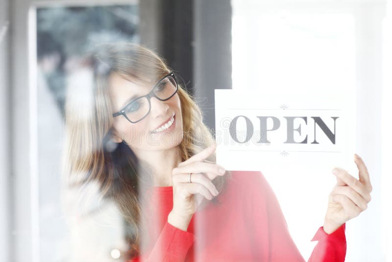 Portrait of middle age small shop owner woman holding in her hands open sign while standing at doorway. Portrait of middle age small shop owner woman holding in her hands open sign while standing at doorway.