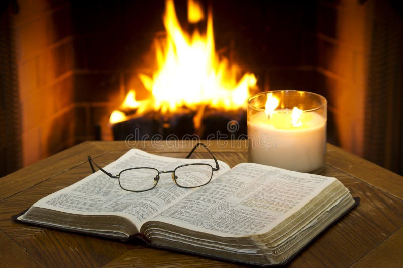 An open Bible on a table in with a fireplace in the background.