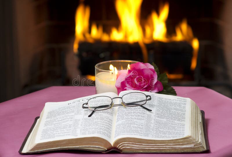 An open Bible on a table in with a fireplace in the background.