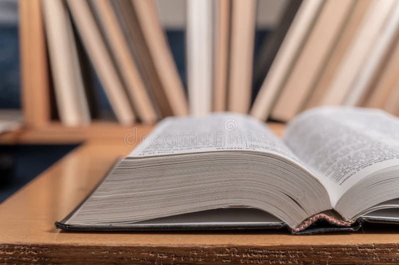 An open book on the background of a bookcase with books, hardback books on a wooden table. Back to school royalty free stock photos
