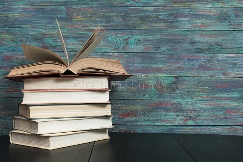 Open book hardback on Stack books on wooden background. Back to school with copy space.
