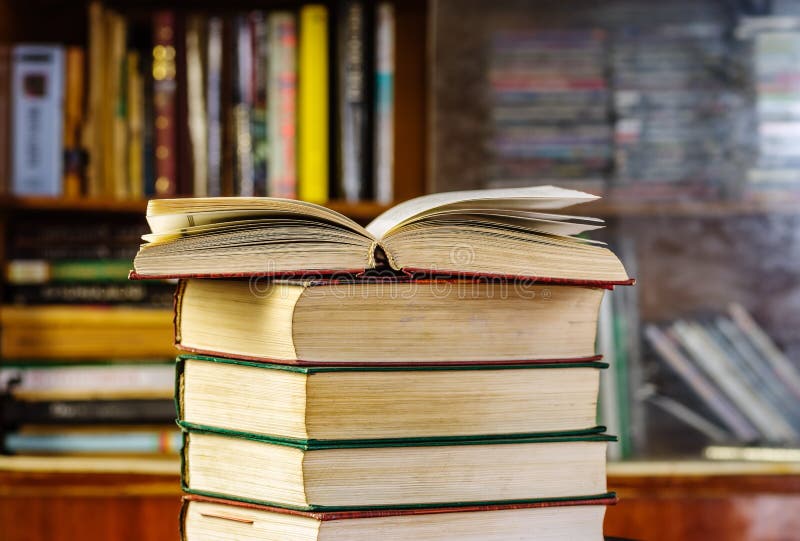 An open book on a stack in front of a bookcase stock photos