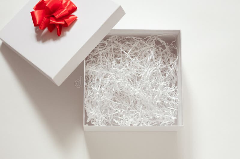 Open box with filler, white gift box with red bow and open lid on white background, mockup for design stock photography