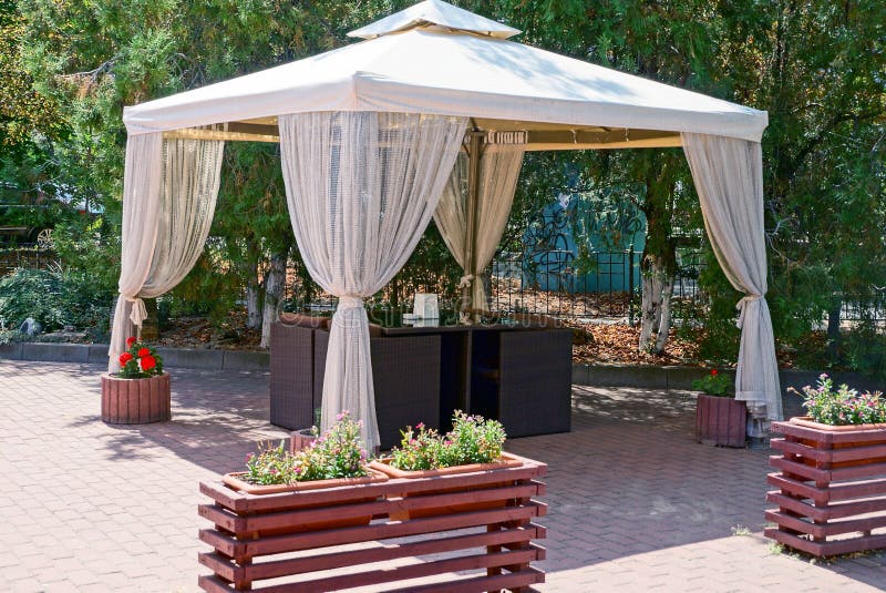 Outdoor gazebo with curtains and furniture on the sidewalk in the park stock photography Outdoor gazebo with curtains and furniture on the sidewalk in the park stock photography
