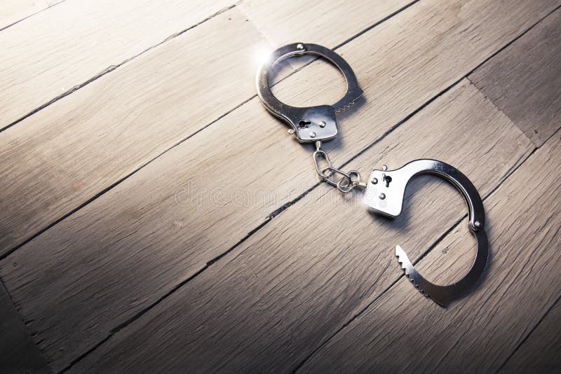 Open Handcuffs on a wooden background stock photography