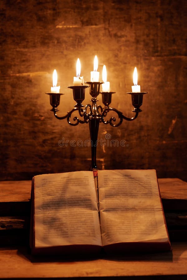 Open Holy Bible and candle on a old oak wooden table. Beautiful gold background. Religion concept