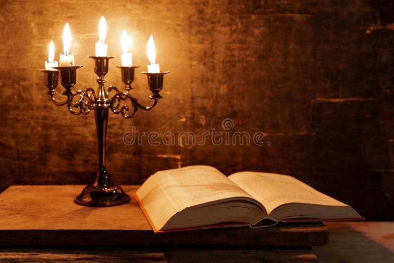 Open Holy Bible and candle on a old oak wooden table. Beautiful gold background. Religion concept