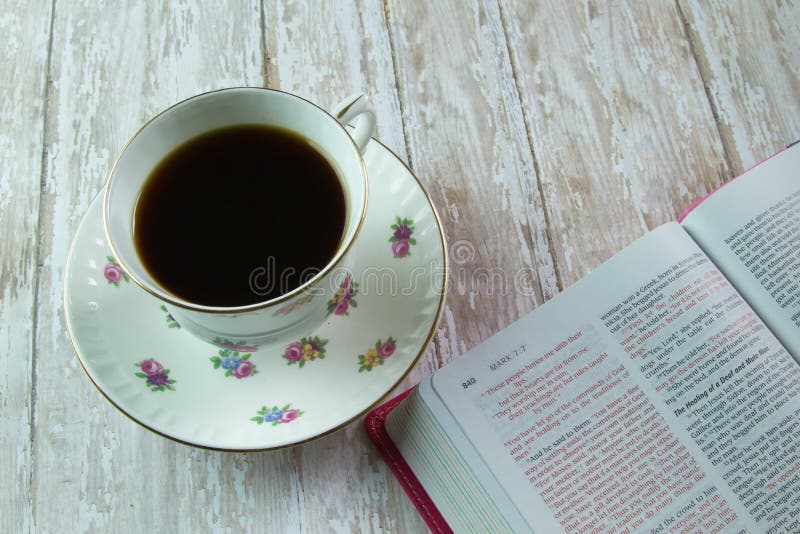 An open Holy Bible and a cup of tea or coffee