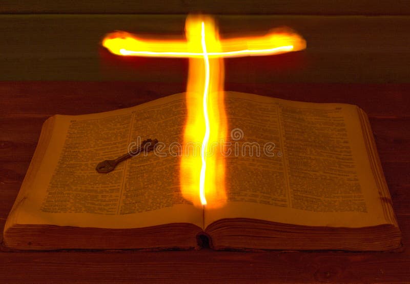 The open Holy Bible is on the table. Ancient key. The Holy Cross glows over the Bible and illuminates its pages. Burning Cross. royalty free stock images The open Holy Bible is on the table. Ancient key. The Holy Cross glows over the Bible and illuminates its pages. Burning Cross. royalty free stock images