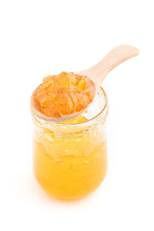 Open jar of orange jam and a spoon, isolated on white.