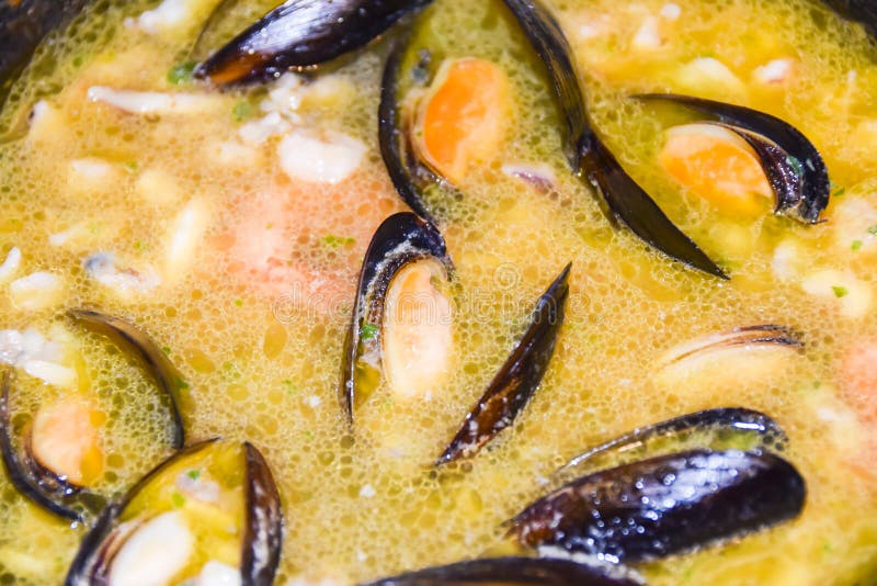 Open Mussels in Orange Broth Cooking in a Frying Pan Stock Photo