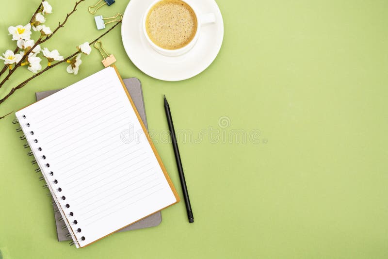Open notebook with empty page and coffee cup. Spring table top, work space on green background. Creative flat lay royalty free stock image