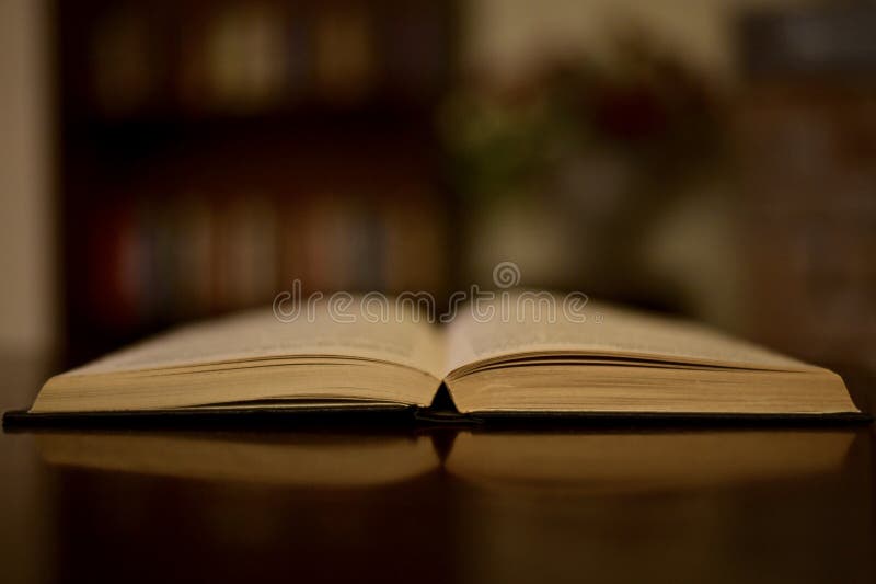 An open old book on a table in a dark library.