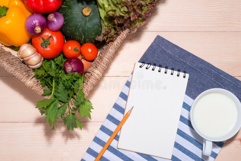 Open Recipe Book with Fresh Vegetables on Wooden Table. Stock Image