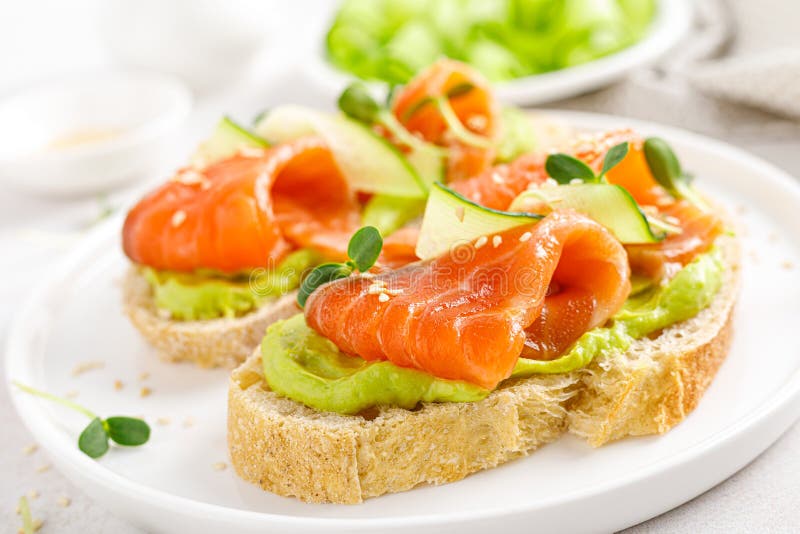 Open sandwiches with salted salmon, guacamole avocado and microgreens. Seafood