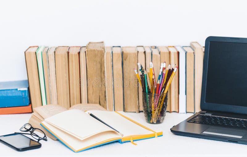 Open textbook, notebook, smartphone, laptop computer, stack of books education back to school background, glasses and pencils in stock photo Open textbook, notebook, smartphone, laptop computer, stack of books education back to school background, glasses and pencils in stock photo