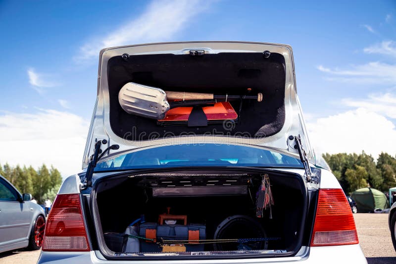 Open the Trunk of a Silver Car that Stands on the Street. in the Trunk of a Shovel, Baseball Bat
