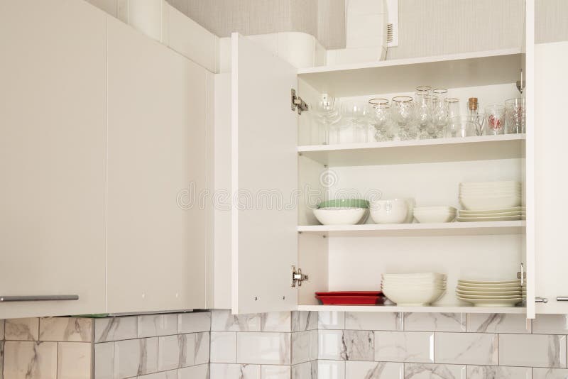Open White Kitchen Door with White Dishes Inside Stock Photo