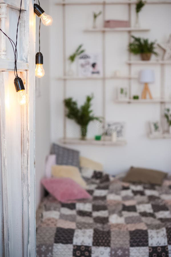 An open white wooden door with luminous lamps. The door to the bedroom is loft style. The bed is in the defocus. Quilt in patchwor. K style. Place and background stock images An open white wooden door with luminous lamps. The door to the bedroom is loft style. The bed is in the defocus. Quilt in patchwor. K style. Place and background stock images