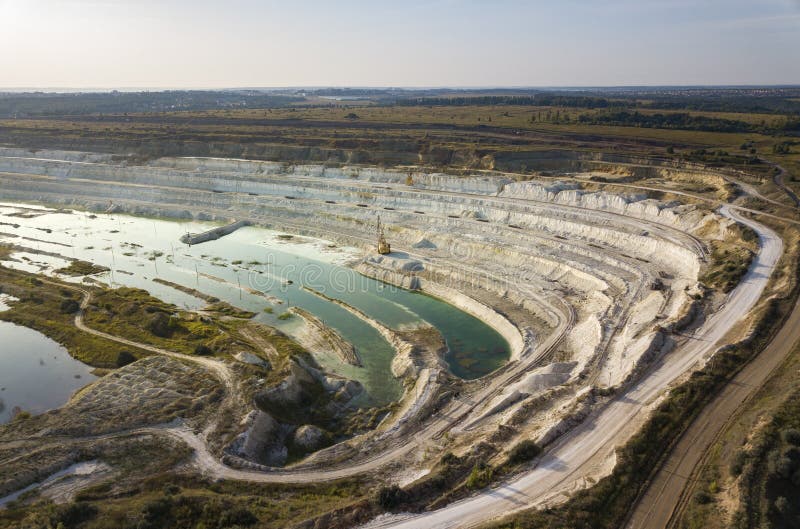 Opencast mining quarry with machinery at work - Aerial view. Industrial Extraction of lime, chalk, calx, caol.