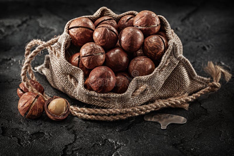 Opened Full of Macadamia Nuts Burlap Bag on Dark Background Stock Photo