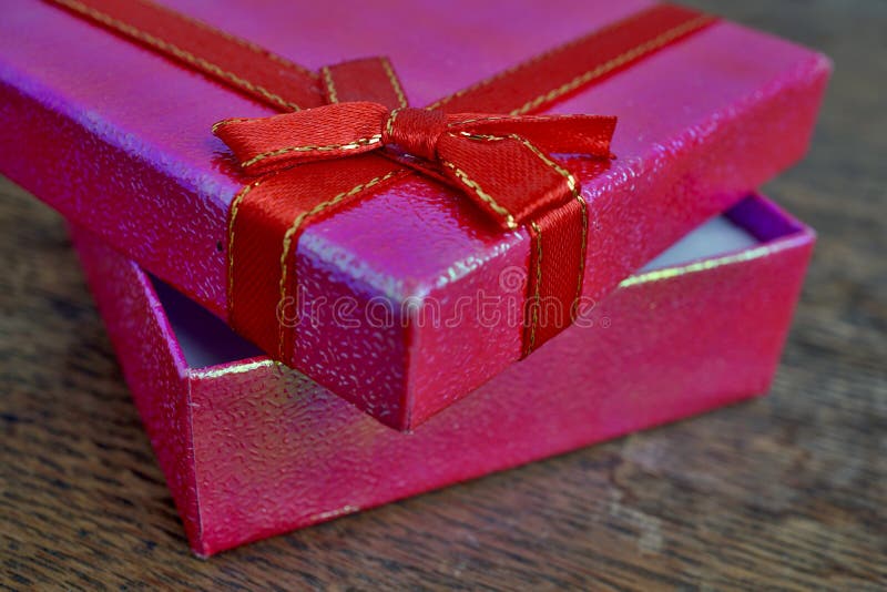 Opened pink gift box with red ribbon and golden stitching on the wooden background as a symbol of giving and getting gifts stock photo Opened pink gift box with red ribbon and golden stitching on the wooden background as a symbol of giving and getting gifts stock photo