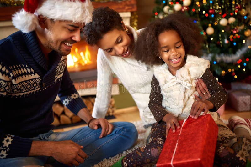 Little afro American little girl opening Christmas present with parents. Little afro American little girl opening Christmas present with parents