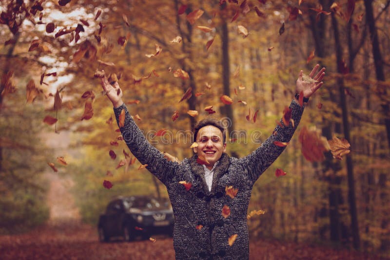 In openlucht portret van de gelukkige jonge mens die zich in de herfstpark bevinden bij stock afbeelding In openlucht portret van de gelukkige jonge mens die zich in de herfstpark bevinden bij stock afbeelding