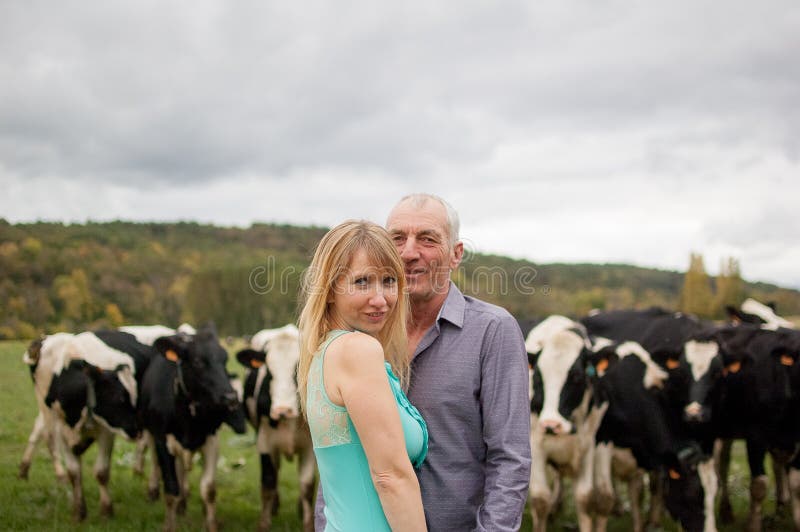 In openlucht Portret van de Landbouwer en Zijn Vrouw die voor Hun Zwart-witte Koeien koesteren royalty-vrije stock afbeeldingen In openlucht Portret van de Landbouwer en Zijn Vrouw die voor Hun Zwart-witte Koeien koesteren royalty-vrije stock afbeeldingen