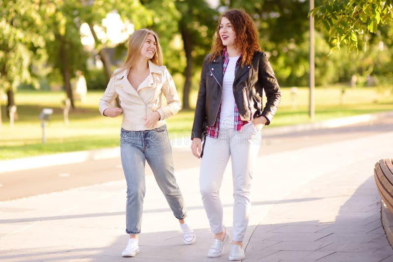In openlucht portret van verrukkelijke jonge vrouw twee Wandeling en praatje van de twee het de Kaukasische meisjesvriend samen i stock afbeelding In openlucht portret van verrukkelijke jonge vrouw twee Wandeling en praatje van de twee het de Kaukasische meisjesvriend samen i stock afbeelding