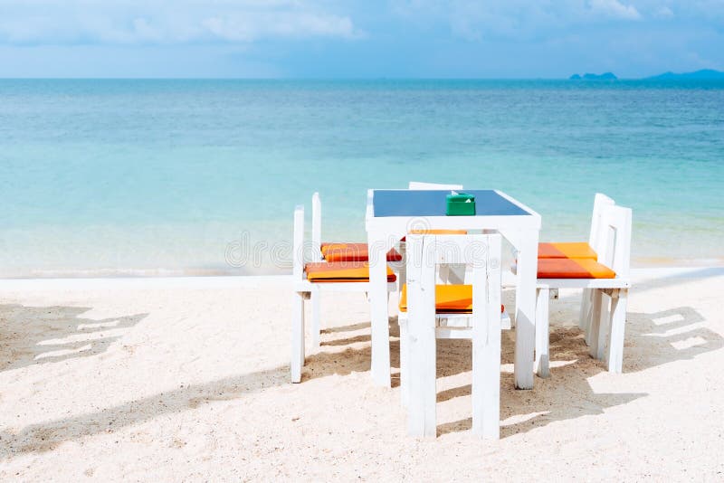 Openlucht witte dinerlijst die op het witte strand plaatsen van de zandzomer stock foto Openlucht witte dinerlijst die op het witte strand plaatsen van de zandzomer stock foto