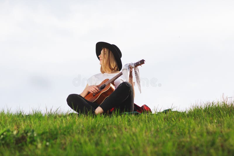 Openluchtportret van een jonge mooie vrouw in zwarte hoed, het spelen gitaar Ruimte voor tekst stock afbeeldingen Openluchtportret van een jonge mooie vrouw in zwarte hoed, het spelen gitaar Ruimte voor tekst stock afbeeldingen
