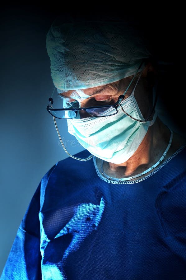 Doctor performing surgery in a dark background. Doctor performing surgery in a dark background