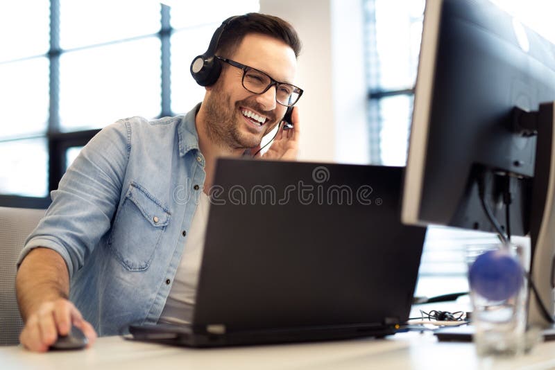 Operador de centro de atención telefónica de sexo masculino sonriente joven que hace su trabajo con auriculares Retrato del traba