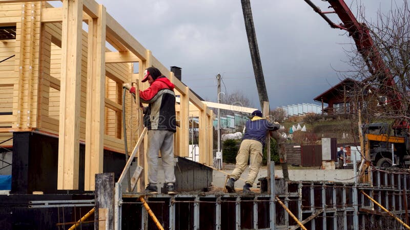 Operai calcestruzzano il muro di tenuta e le fondamenta per la terraferma utilizzando i lavori di formazione