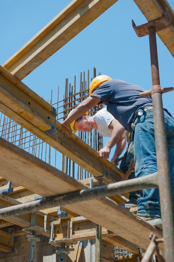 Authentic construction workers placing slab formwork beams in construction site. Authentic construction workers placing slab formwork beams in construction site