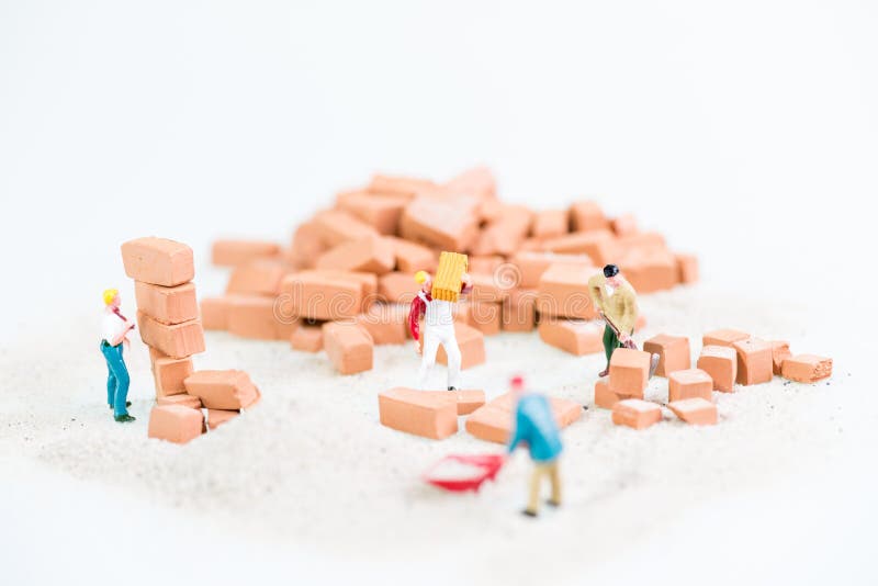 Operai miniatura che lavorano insieme nella stenditura dei mattoni fotografia stock Operai miniatura che lavorano insieme nella stenditura dei mattoni fotografia stock