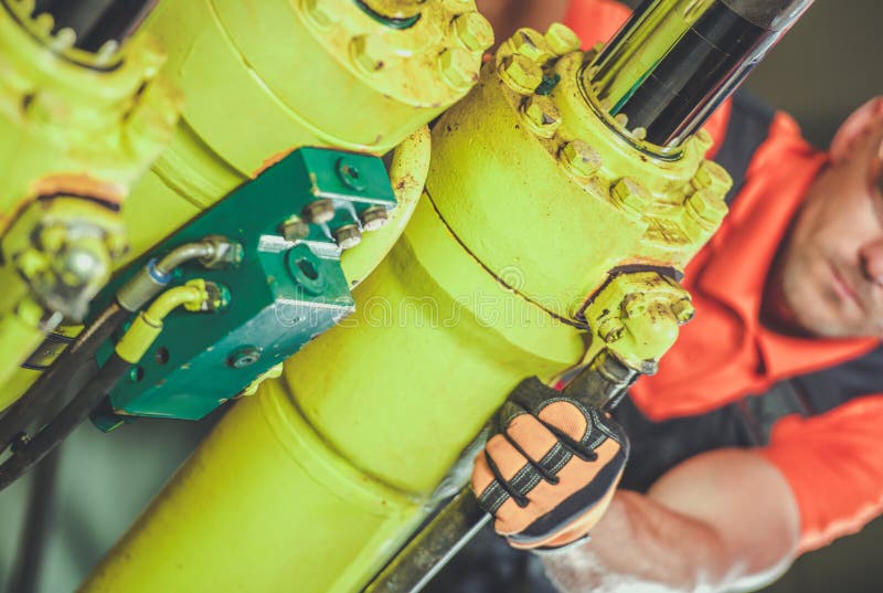 Operaio che utilizza chiave su macchine idrauliche in impianti industriali durante il giorno fotografia stock libera da diritti