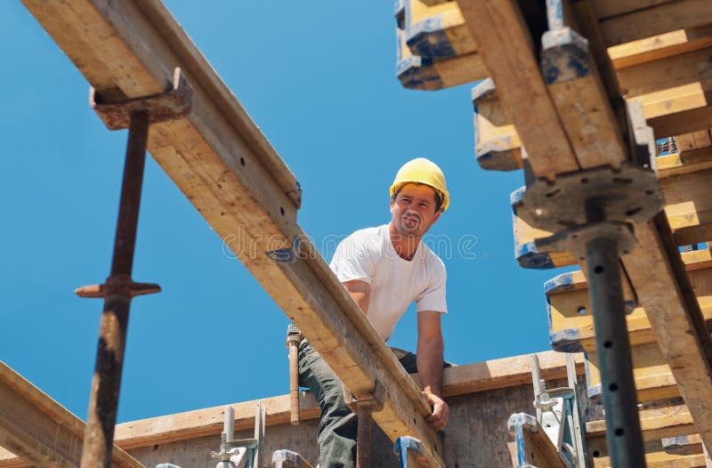 Authentic construction worker placing slab formwork beams in construction site. Authentic construction worker placing slab formwork beams in construction site