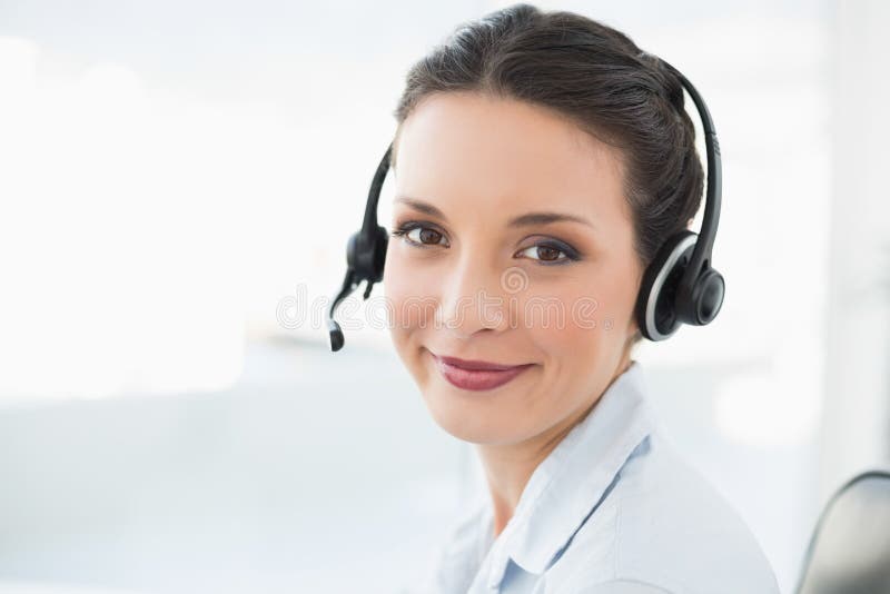 Operatore castana alla moda contento che sorride e che esamina macchina fotografica fotografie stock libere da diritti Operatore castana alla moda contento che sorride e che esamina macchina fotografica fotografie stock libere da diritti