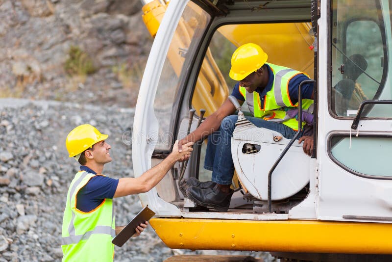 Happy construction manager handshaking with bulldozer operator at construction site. Happy construction manager handshaking with bulldozer operator at construction site